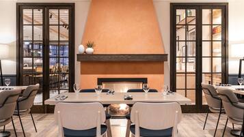 A dining area with a large table, chairs, and a fireplace.