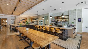 A spacious kitchen with a long wooden table, bar area, and hanging pendant lights. - Best Western Plus Baker Street Inn (Nelson)