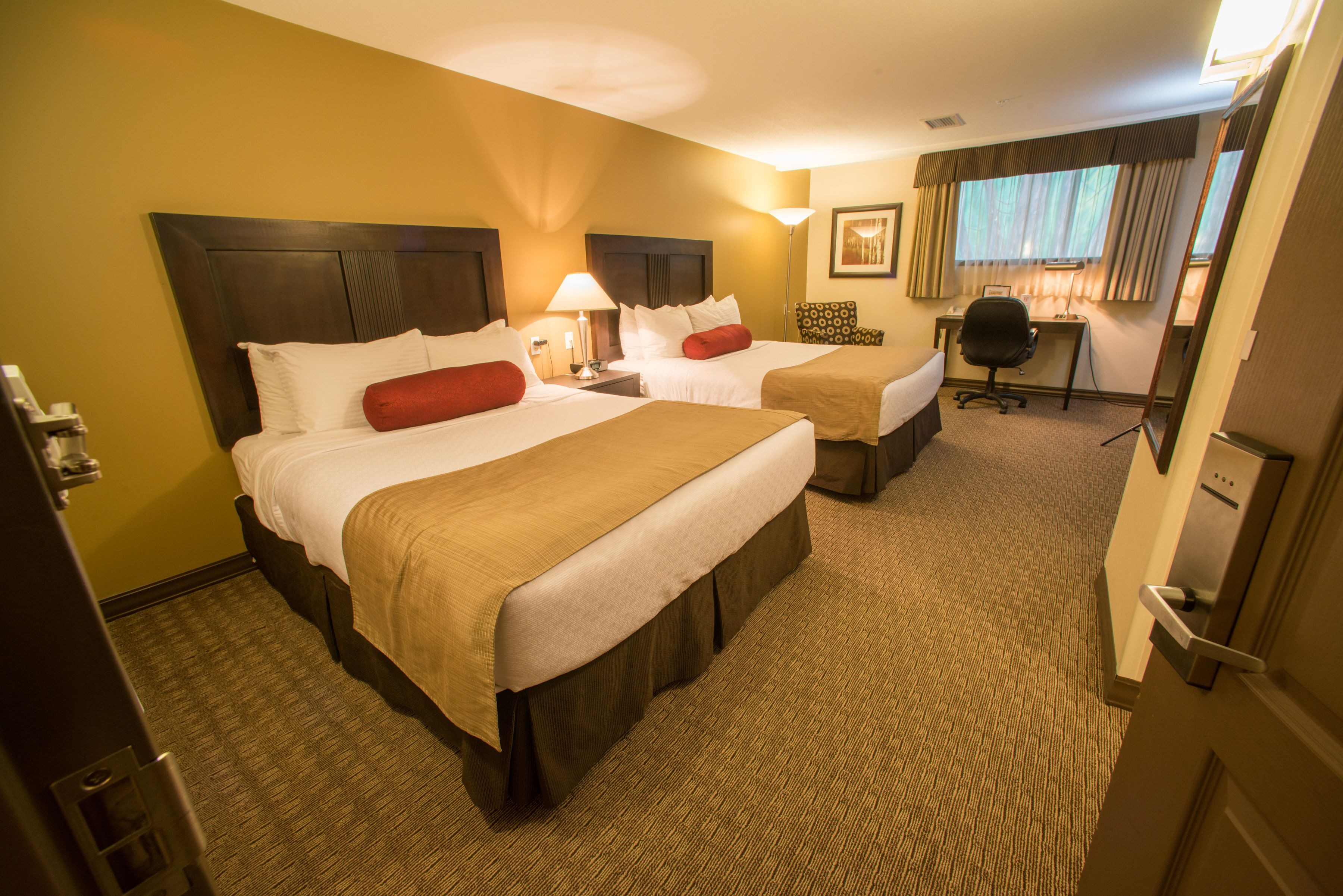 Quarto de hotel com duas camas, uma escrivaninha e uma cadeira.
