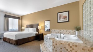 A hotel room with a large bed, a separate bathroom with a bathtub, and a window with curtains. - Best Western Plus Baker Street Inn (Nelson)