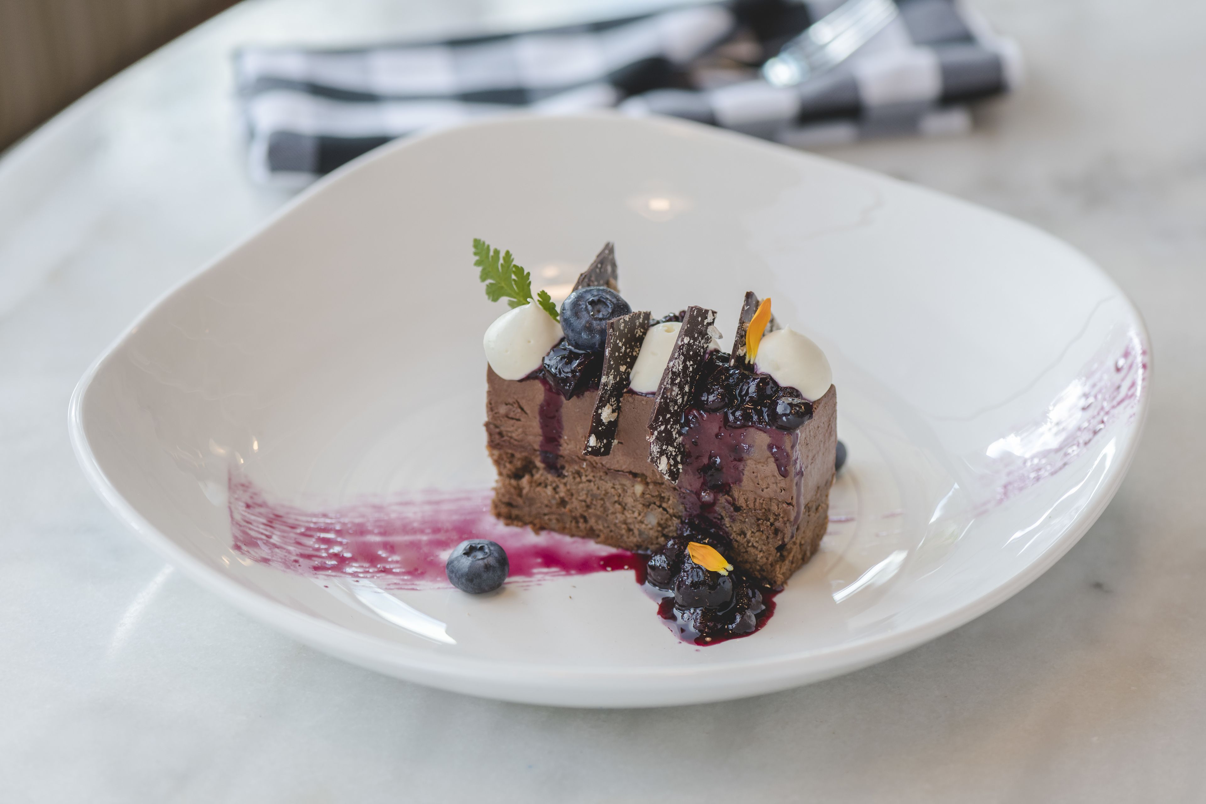 Un postre sobre un plato blanco, con un mantel a cuadros al fondo.