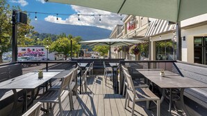 An outdoor patio with tables and chairs, a mountain view, and a building with a sign reading "Best Western Plus". - Best Western Plus Baker Street Inn (Nelson)