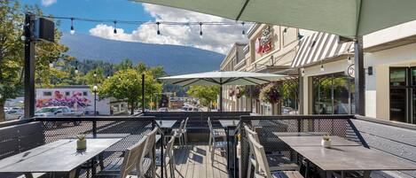 Une terrasse extérieure avec des tables et des chaises, une vue sur les montagnes et un bâtiment portant une enseigne indiquant « Best Western Plus ».