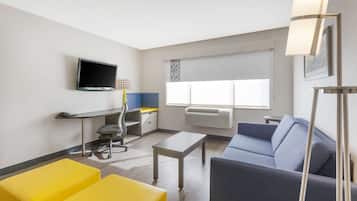 Una habitación de hotel moderna con una televisión de pantalla plana, un escritorio con una silla, un sofá y una mesa de centro.