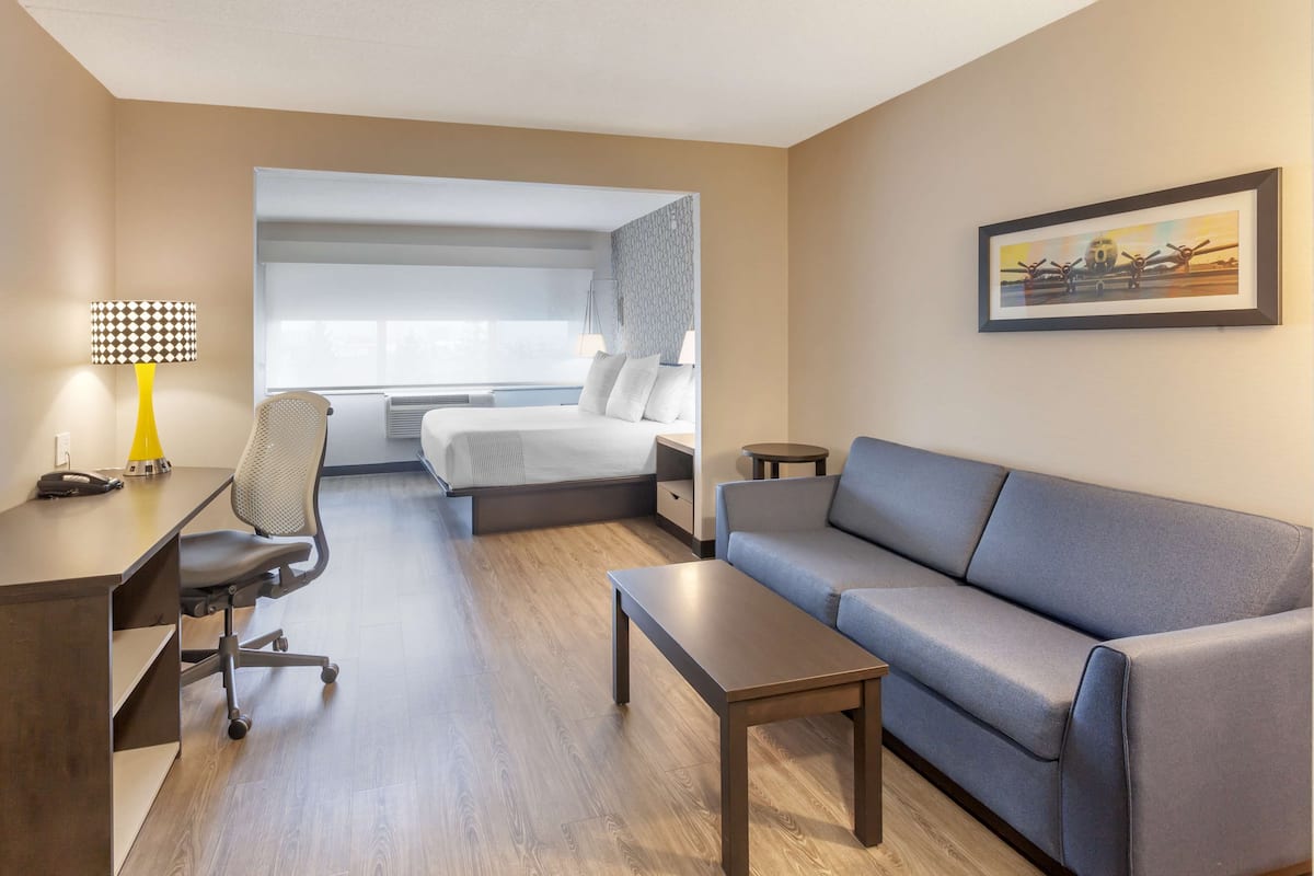 Una habitación de hotel con cama, escritorio, silla, sofá y una mesita.