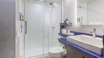 A modern bathroom with a glass-enclosed shower, a white toilet, and a sink with a blue countertop.