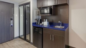 Una cocina moderna con armarios de madera oscura, un lavamanos de acero inoxidable y un microondas integrado.
