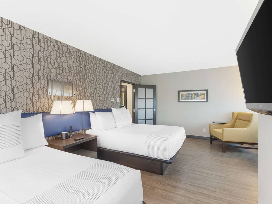Habitación de hotel con dos camas, un escritorio, una silla y un televisor.