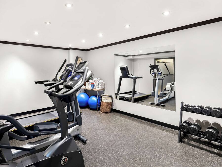 A gym with treadmills, a mirrored wall, and a rack of dumbbells.