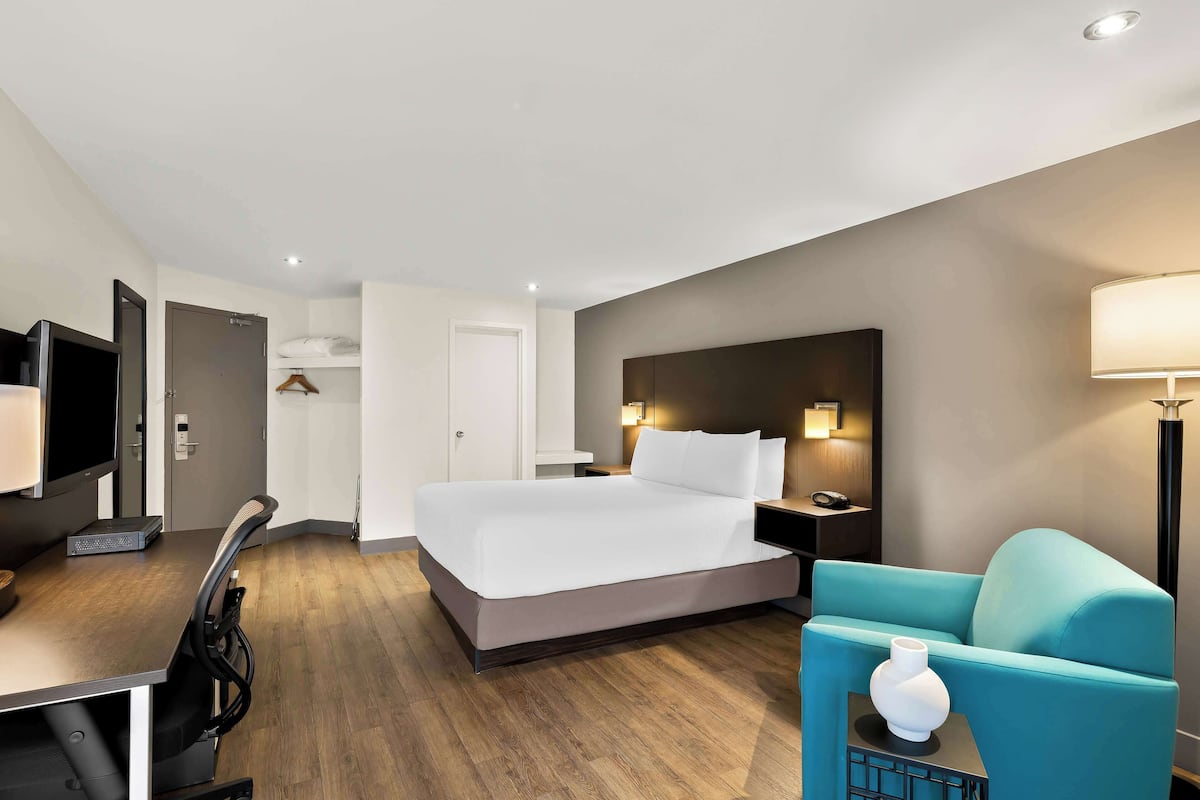 Ein modernes Hotelzimmer mit Bett, Schreibtisch, Stuhl und Fernseher.