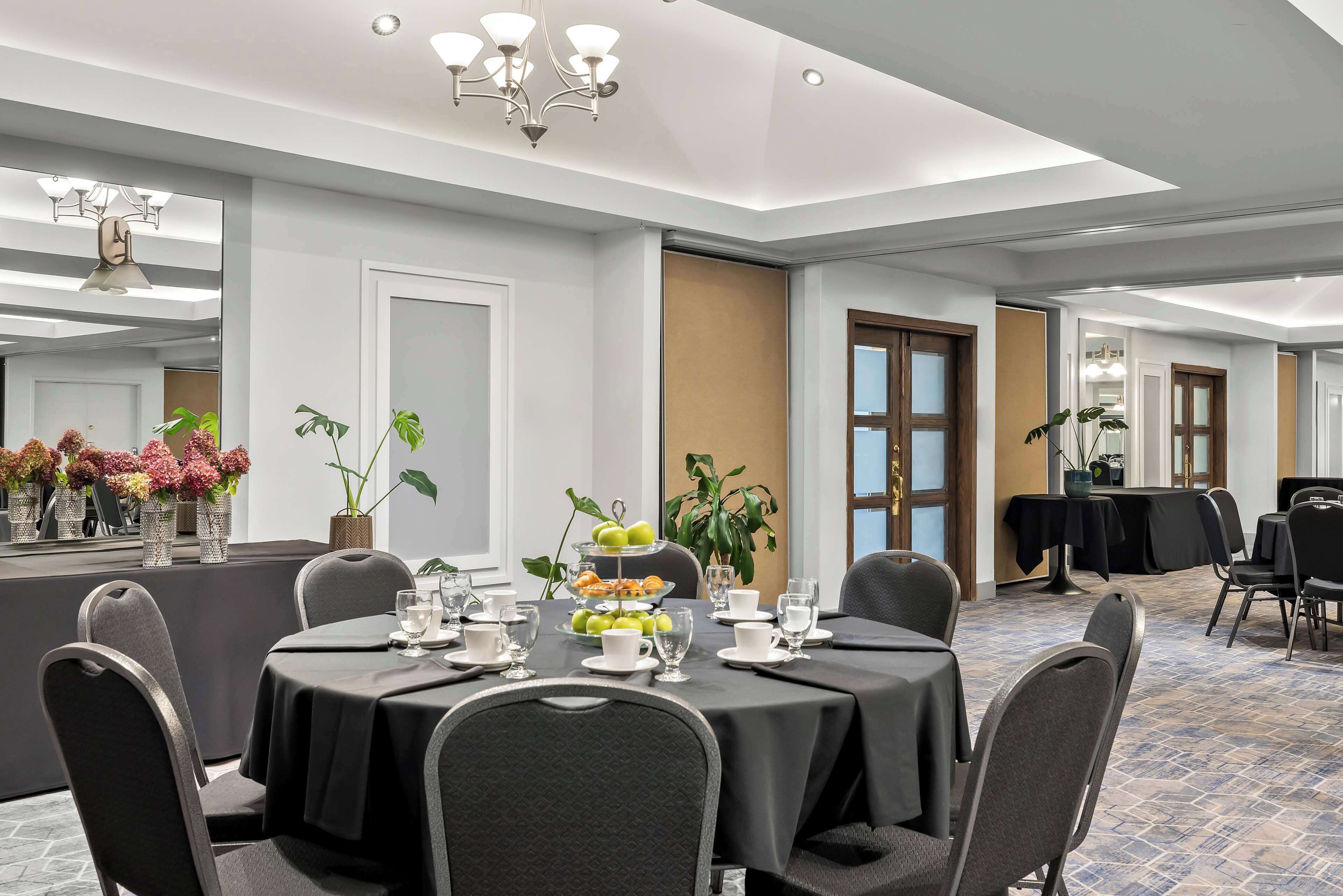 Un salón de conferencias con una mesa redonda, sillas y una bandeja escalonada de fruta.
