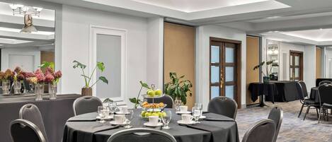 A conference room with a round table, chairs, and a tiered fruit display.