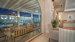 A modern lounge area with a pool view, featuring comfortable seating and a large glass wall.