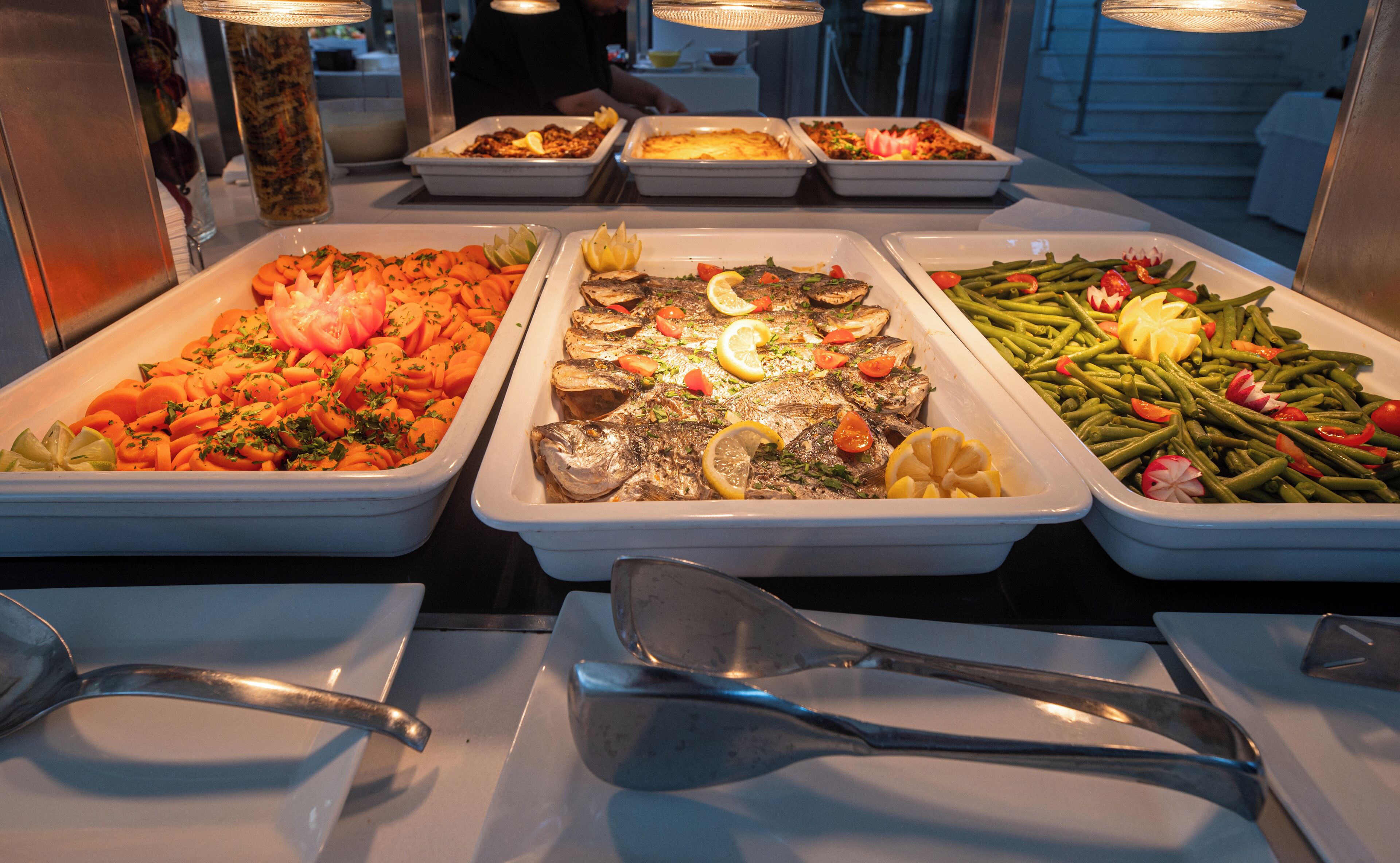A buffet with various dishes including fish, vegetables, and salads.