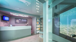 A modern spa reception area with a reception desk, a digital screen, and a glass wall displaying an underwater scene. - Zante Park Resort & Spa, BW Premier Collection (Zakynthos)