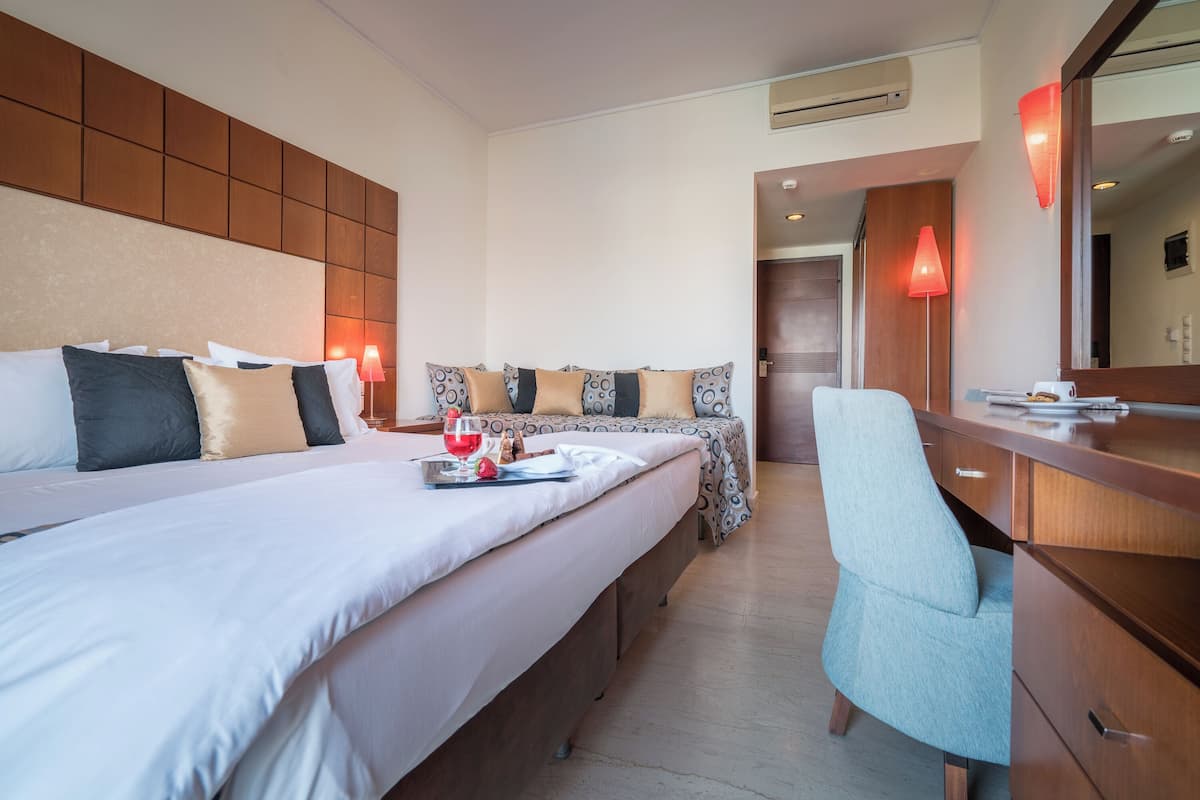 A hotel room with two beds, a desk, and a chair.