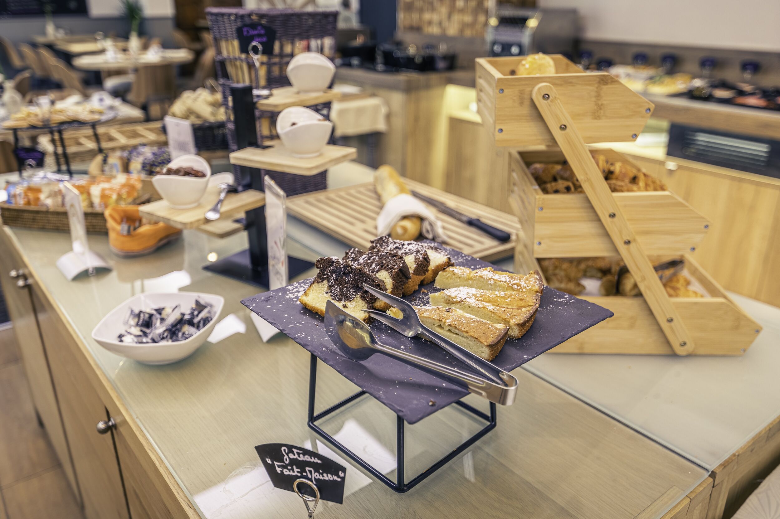 A buffet with various food items, including bread, pastries, and a sign indicating a special menu.
