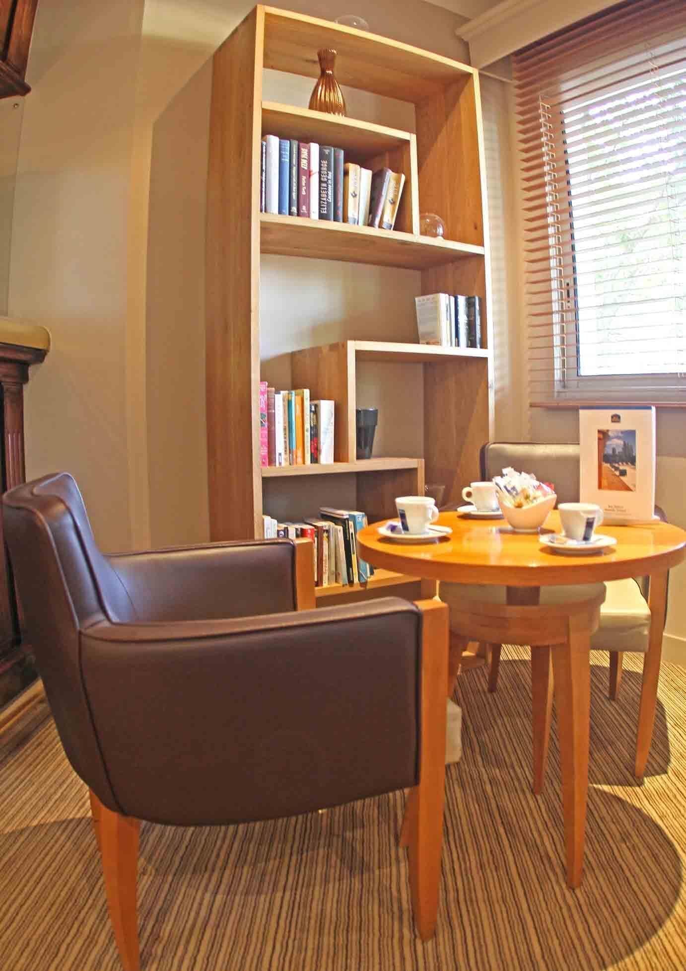 A cozy reading area with a leather chair, a wooden table, and a bookshelf filled with books.