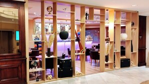 Un hall d’hôtel avec une cloison en bois, un espace salon et un bar.