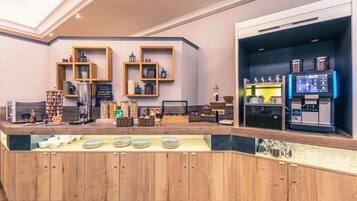 Una cafetería moderna con estanterías de madera, una máquina de café y una exhibición de platos y tazas.