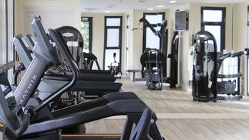 Un gimnasio con cintas de correr, máquinas de pesas y equipo de ejercicio.