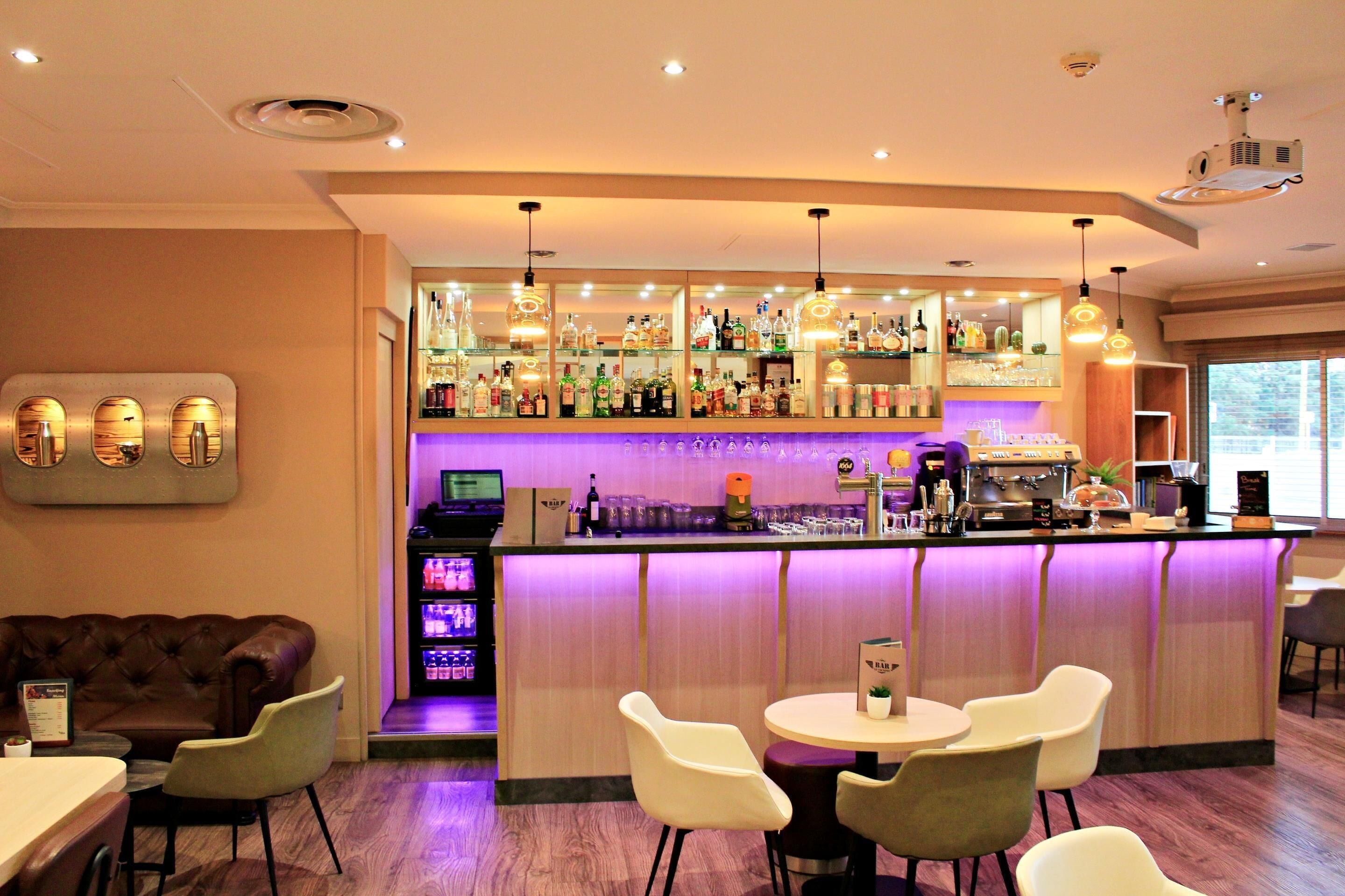 A bar area with a counter, seating, and a variety of bottles and glasses.