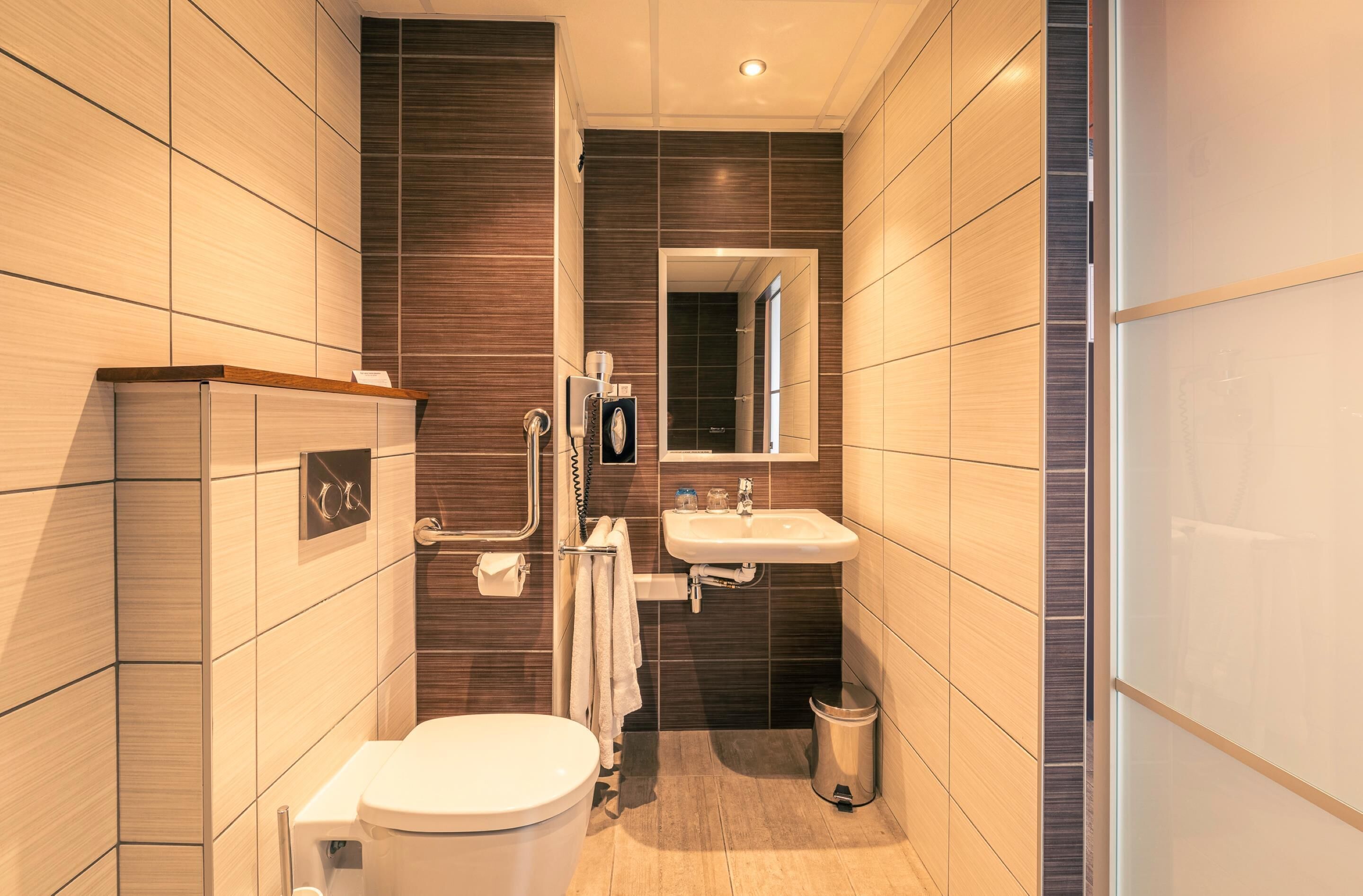 Un baño moderno con inodoro, lavamanos y espejo.