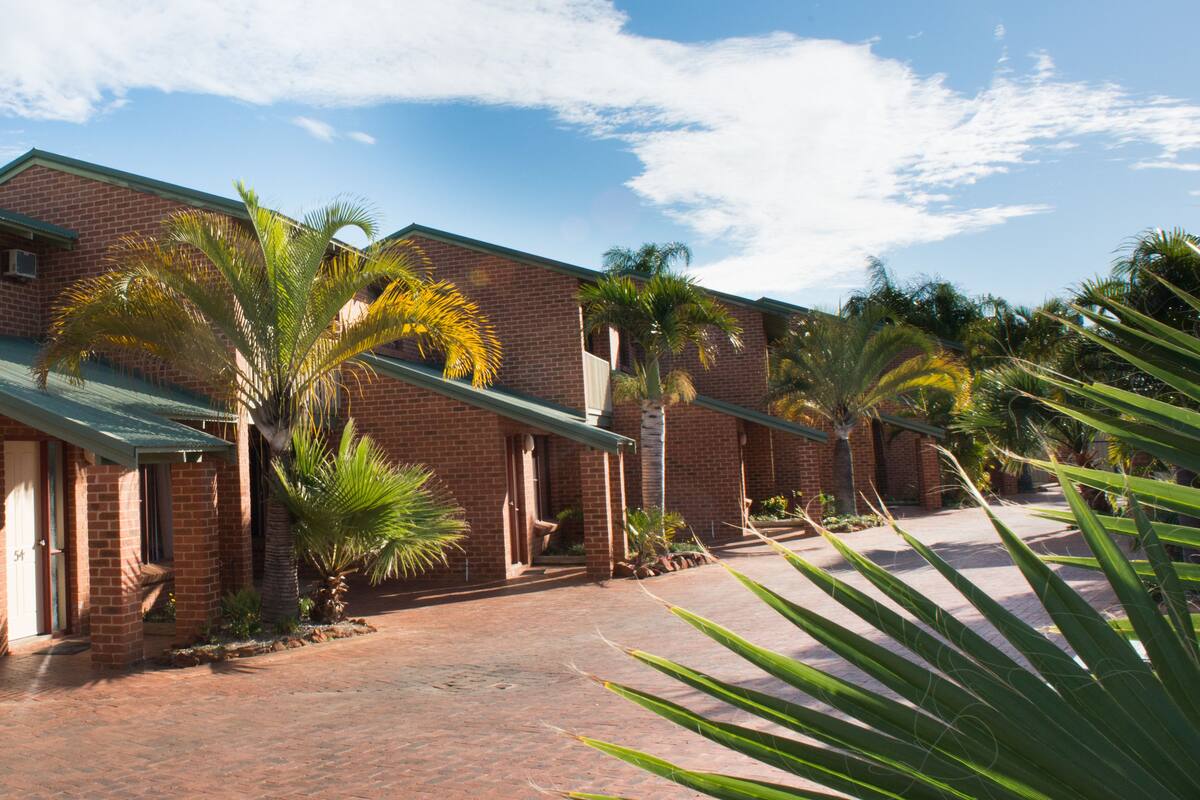 A brick building with a covered walkway and palm trees.