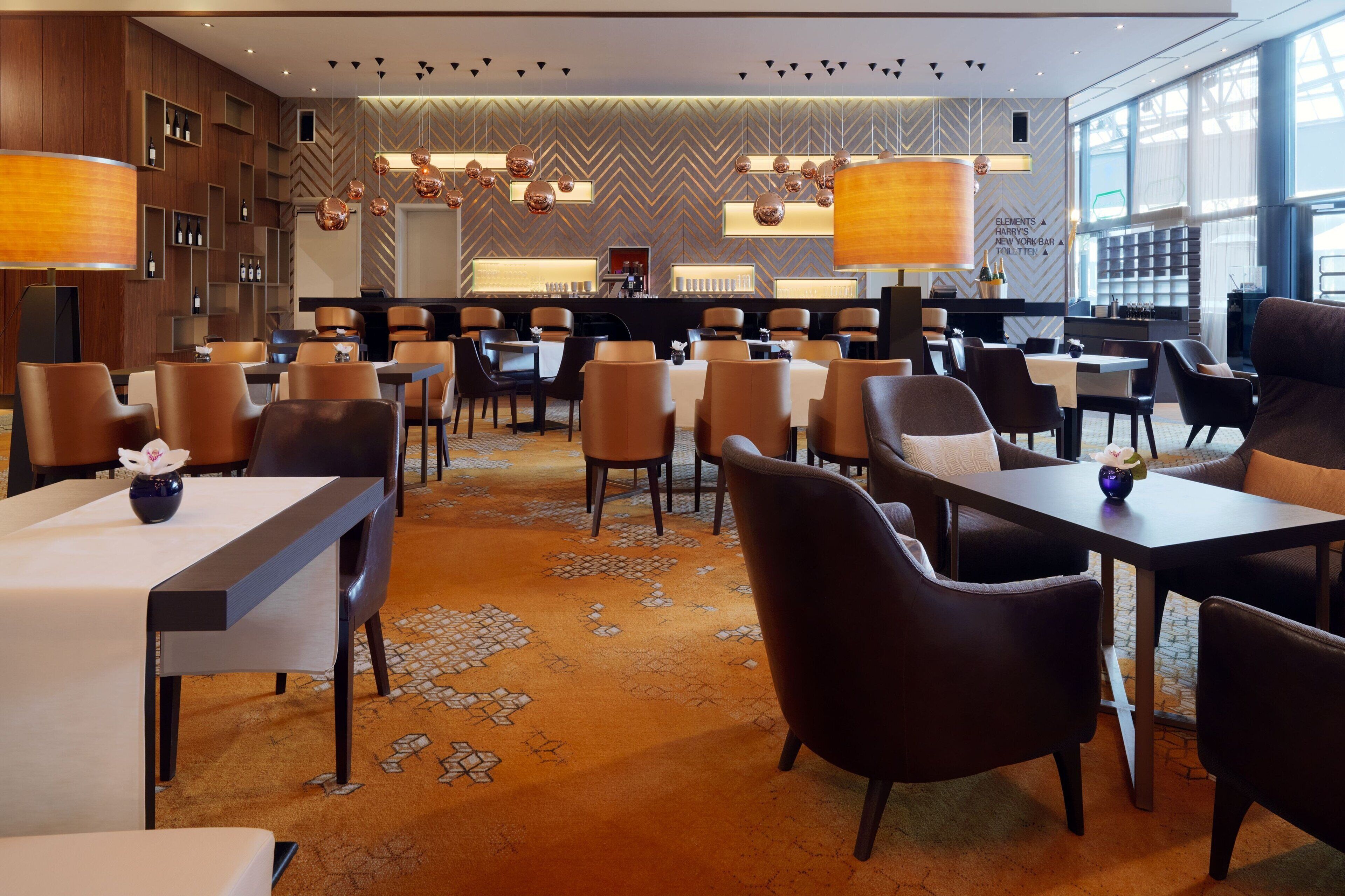 Un moderno vestíbulo de hotel con zona de bar, asientos y un suelo con diseño.