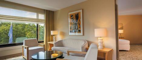 Une chambre d’hôtel avec un canapé, des fauteuils, une table basse et un tableau au mur.