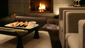 Un salon confortable avec une cheminée, une table à manger où sont servis des sushis et des sièges confortables.