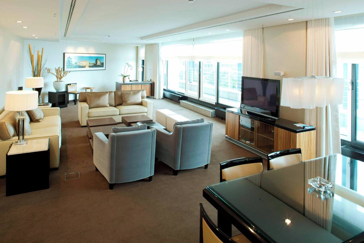 Une chambre d’hôtel moderne dotée d’un espace salon comprenant un canapé, une table à manger et un téléviseur à écran plat.