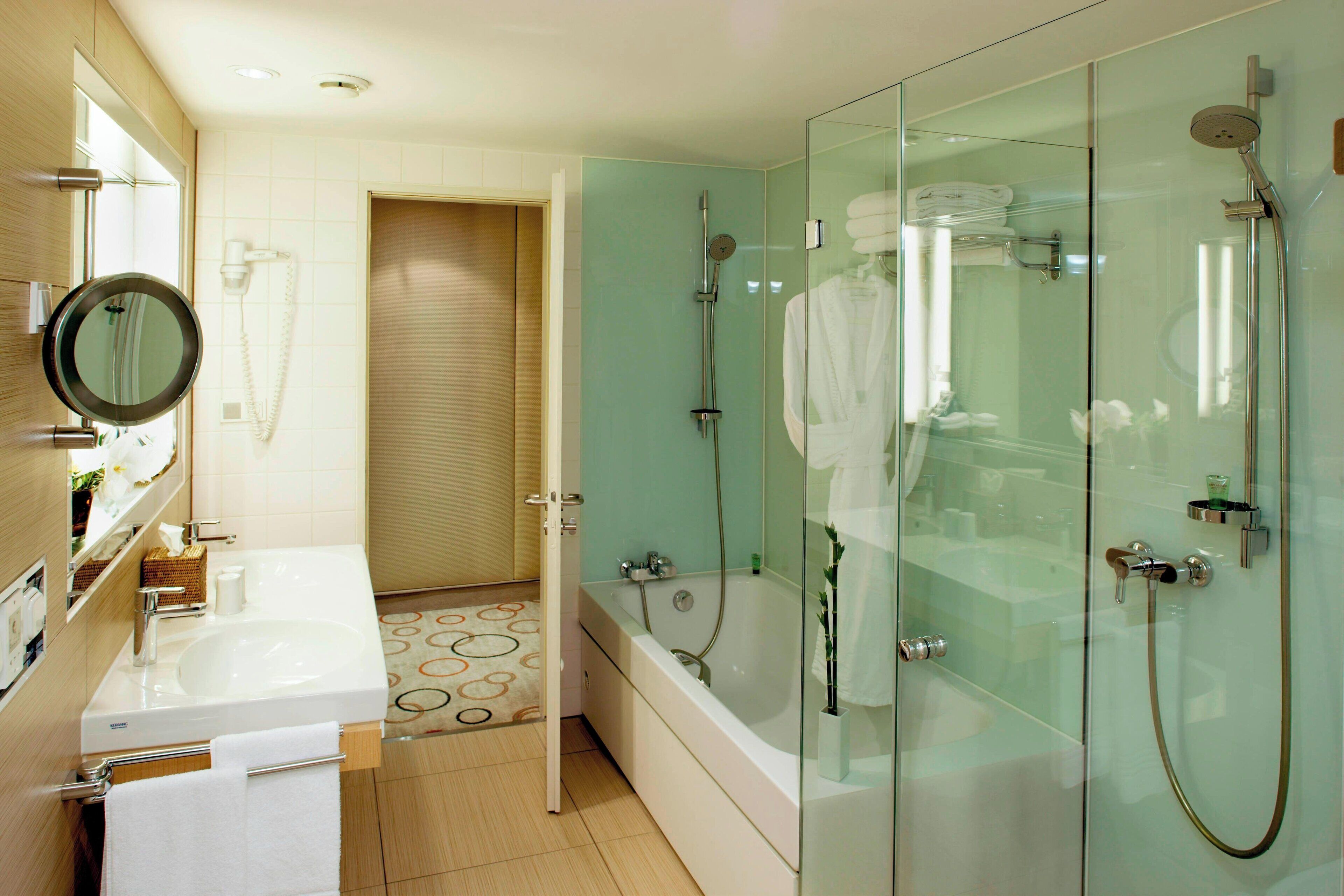 Un baño moderno con ducha envuelta en vidrio, lavamanos doble y bañera.