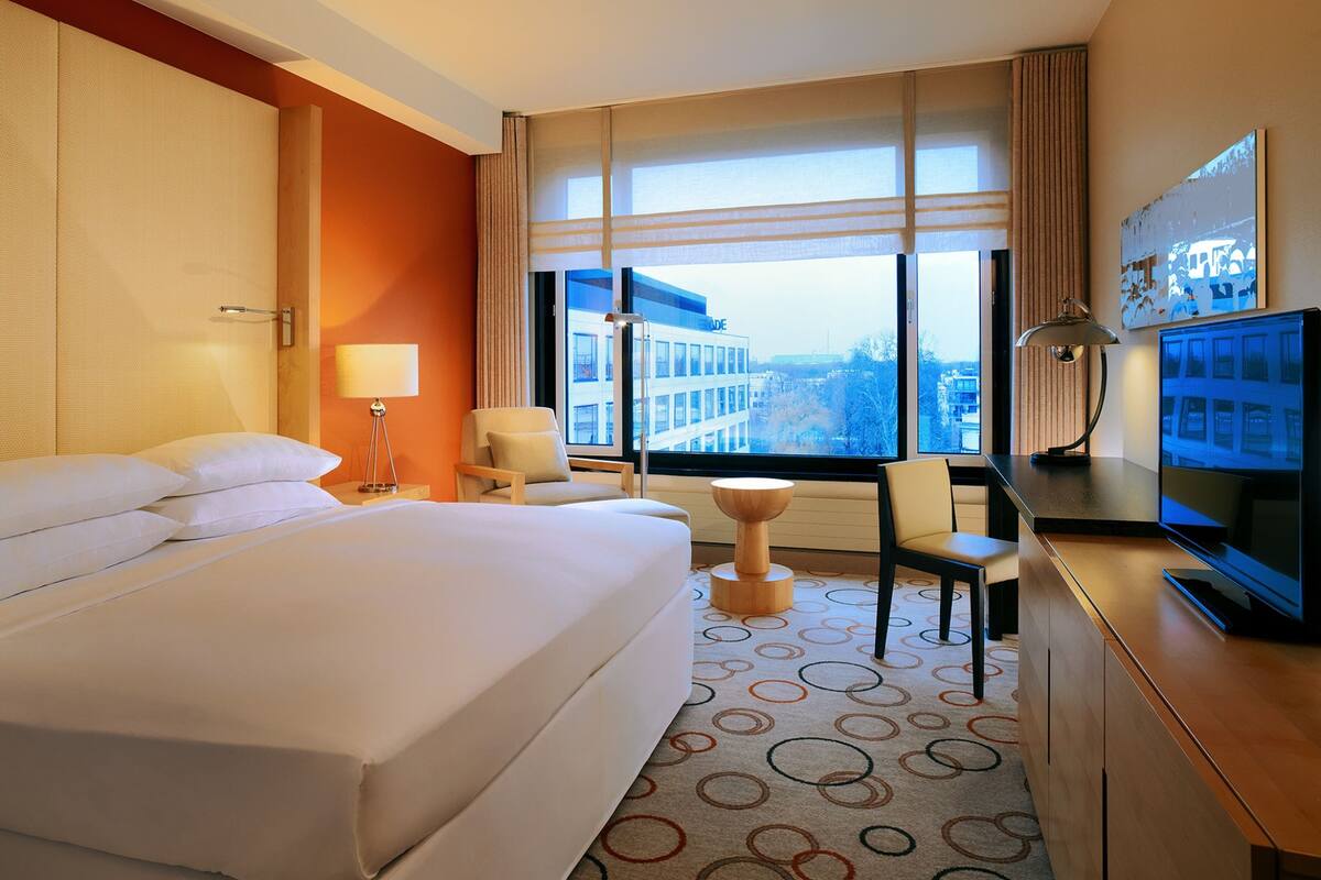 Une chambre d’hôtel avec un grand lit, un bureau avec un ordinateur, une chaise et un téléviseur.
