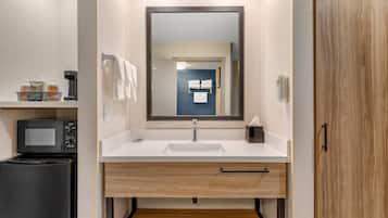 Un baño moderno con un lavabo blanco, un espejo, un perchero y un microondas.