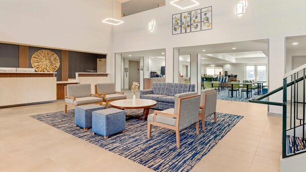 A spacious lobby with a reception desk, seating area, and a staircase leading to upper floors.