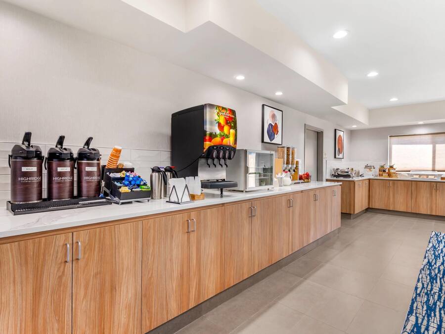A modern kitchen with a coffee station, wooden cabinets, and a large window.