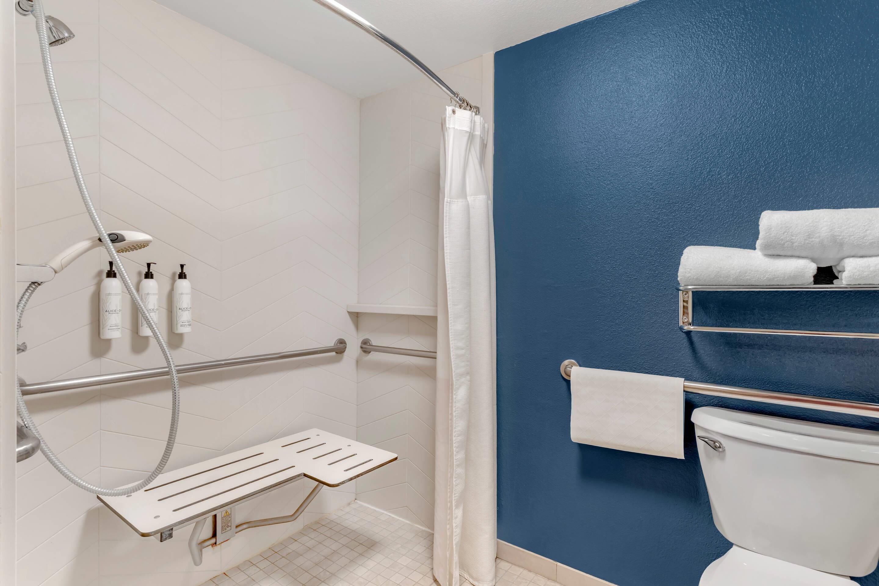 A bathroom with a shower, toilet, and towel rack.