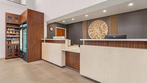 A reception area with a wooden cabinet containing snacks, a refrigerator, and a Dell laptop on a counter.