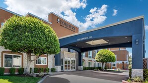 A Country Inn & Suites hotel entrance with a clear sky, a large tree in front, and a sign indicating a 11ft clearance.