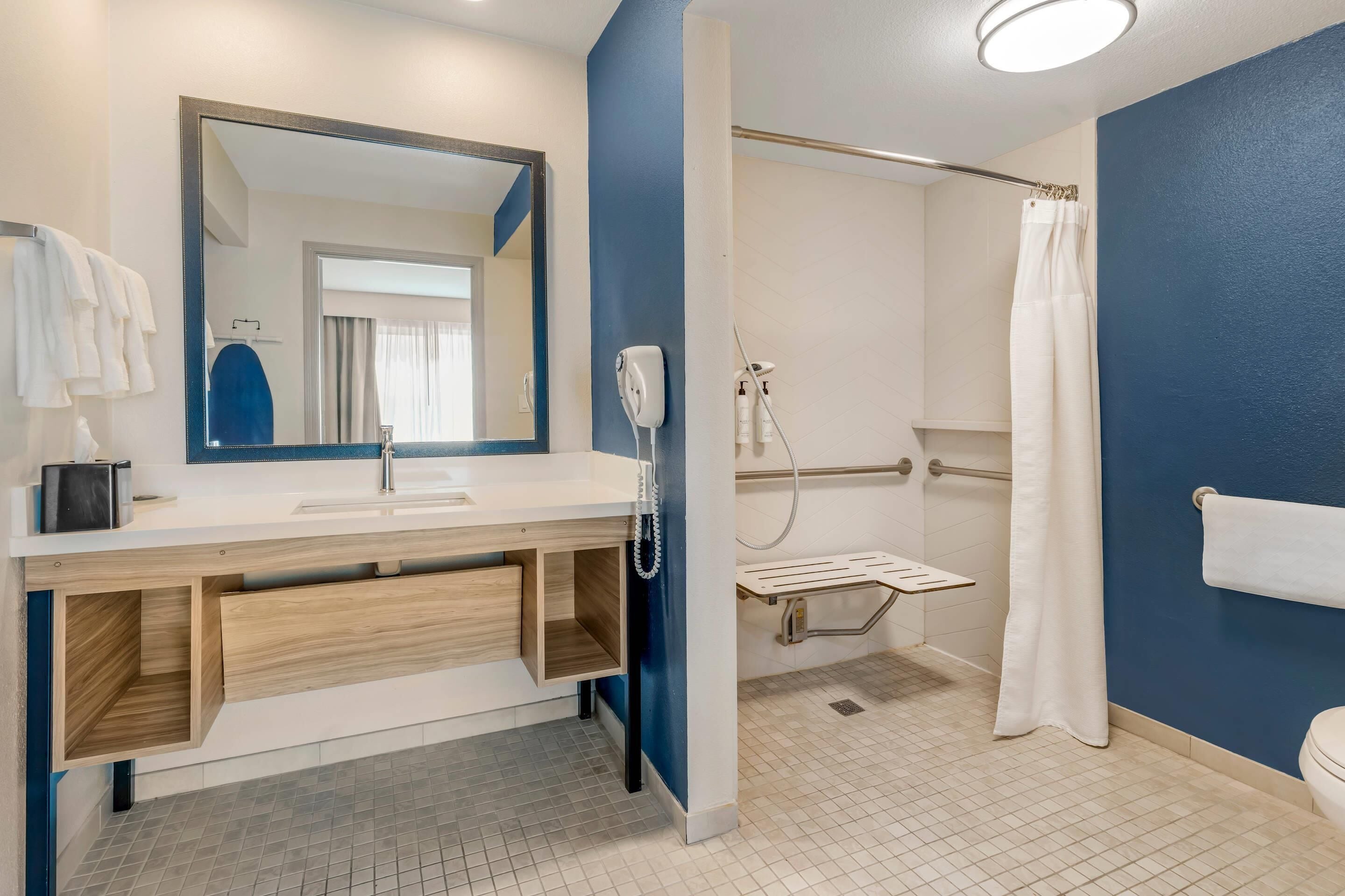 Un baño moderno con lavamanos, espejo y ducha blancos.