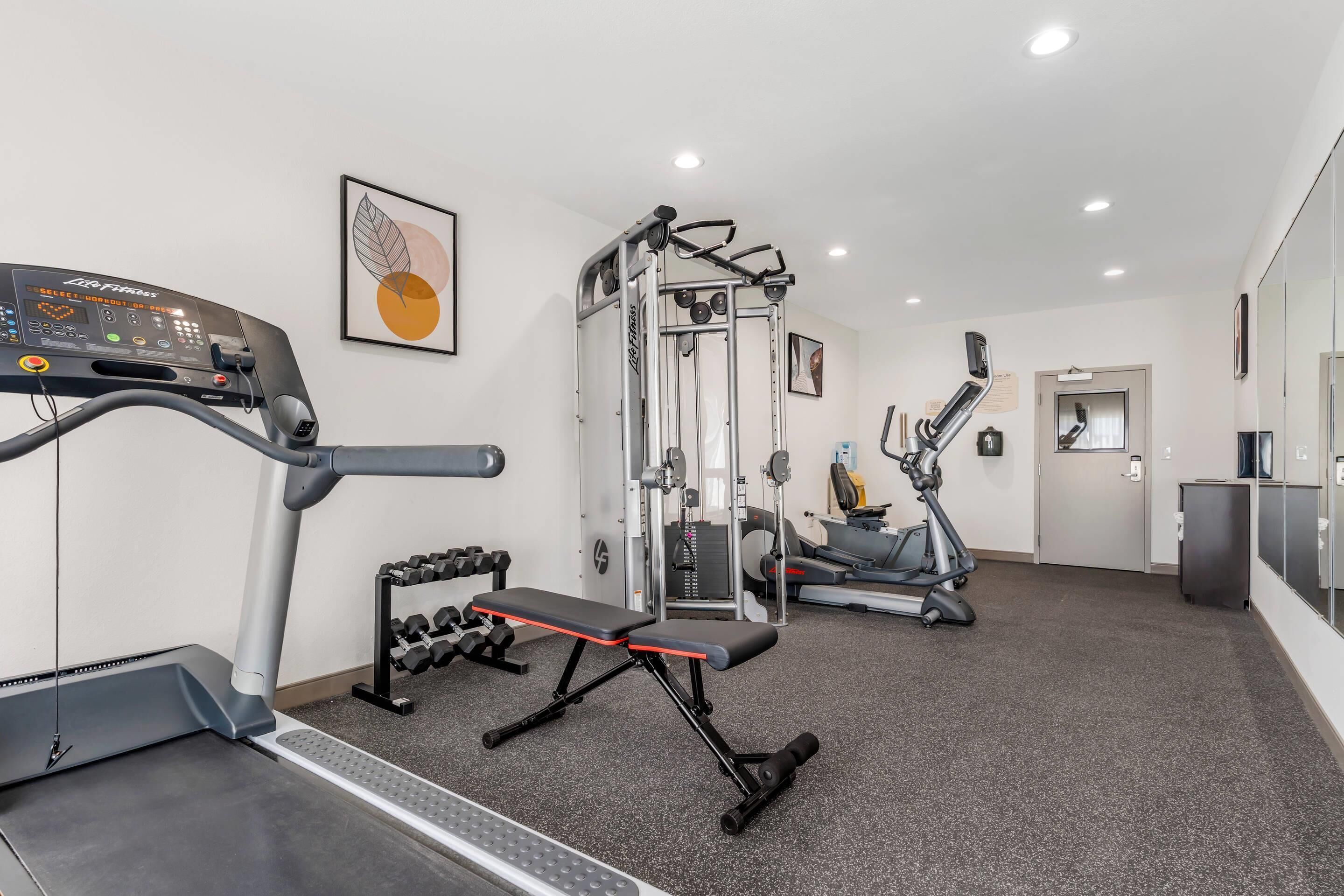 Ein Fitnessstudio mit Cardiogeräten, Krafttrainingsgeräten und Kurzhanteln.