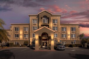 A multi-story hotel with a central entrance, large windows, and a parking lot. - Comfort Inn Lathrop - Stockton Airport (Lathrop)