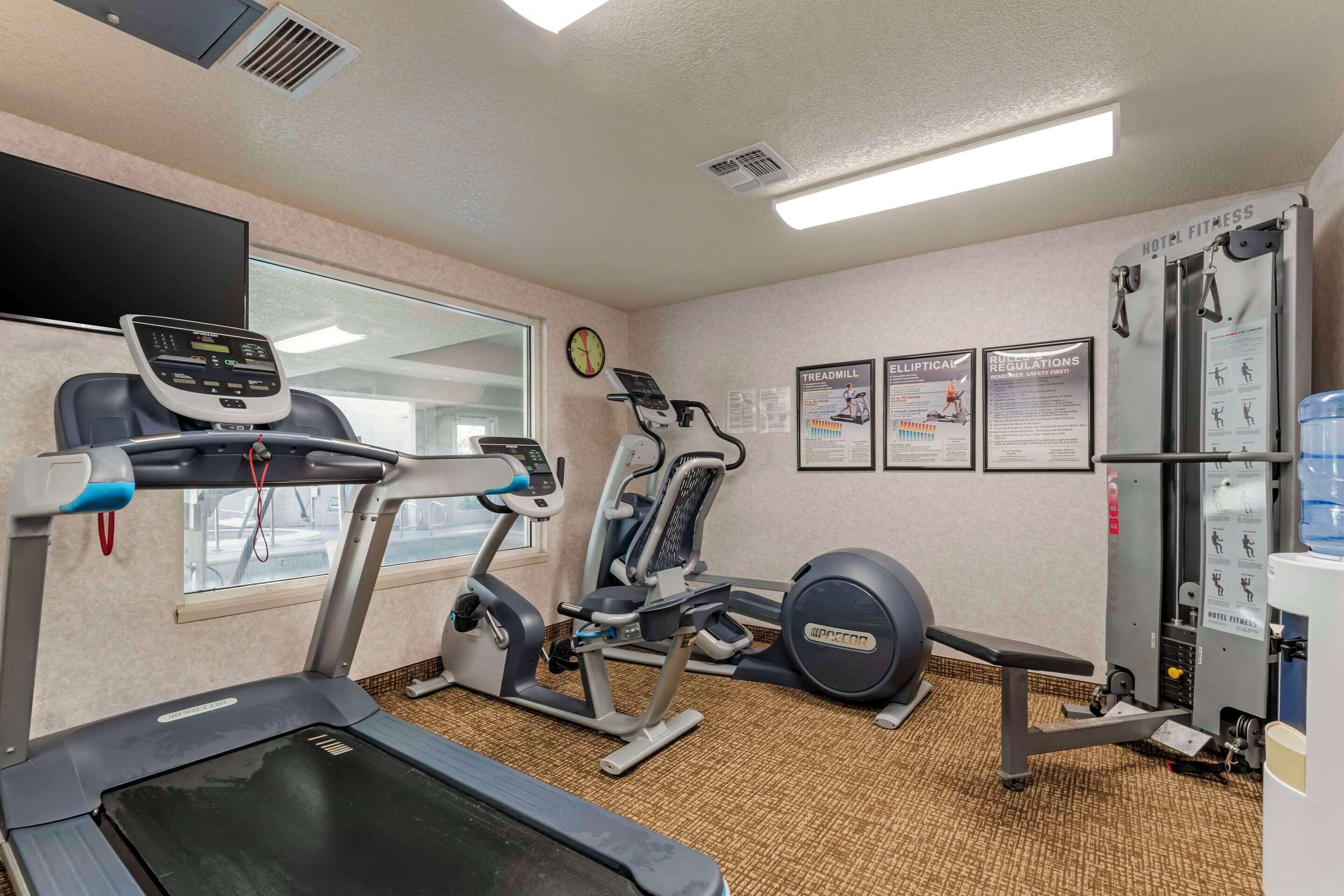A hotel fitness room with a treadmill, elliptical, and weight machine.
