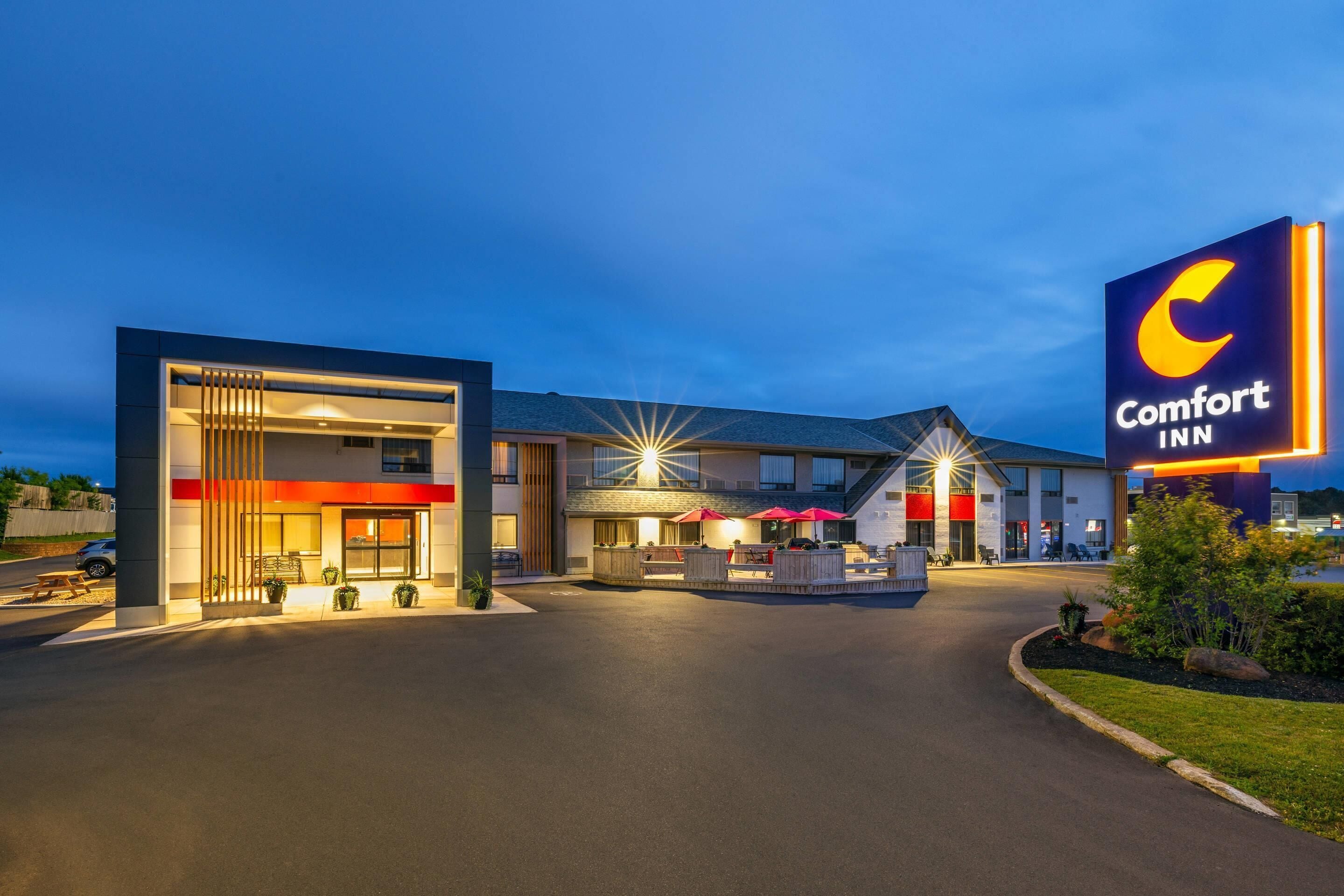 A Comfort Inn hotel with a modern design, featuring a prominent sign, outdoor seating area, and a well-lit entrance.