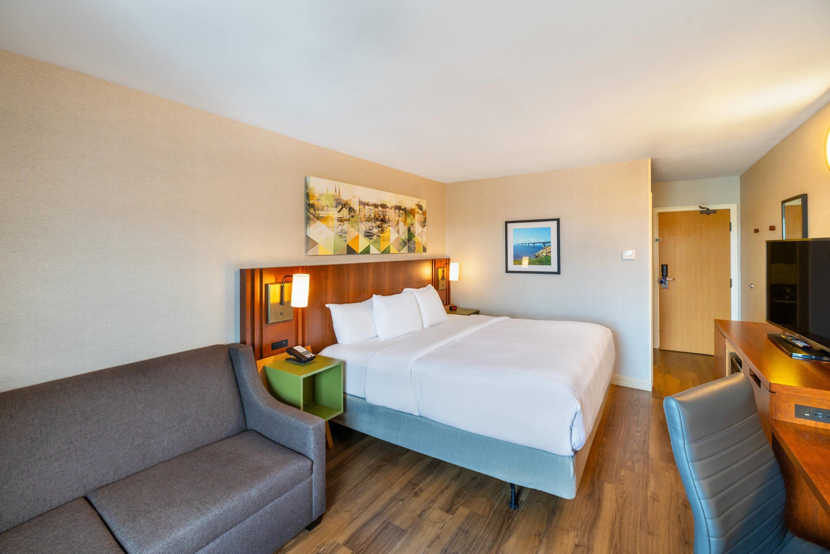 Une chambre d’hôtel avec un lit, un canapé, un bureau et une chaise.