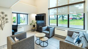 A modern living room with grey sofas, a round wooden table, a fireplace, and a TV. - Comfort Inn Charlottetown (Charlottetown)