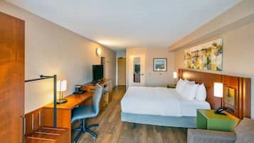 Ein Hotelzimmer mit Bett, Schreibtisch, Stuhl und einem Gemälde an der Wand.