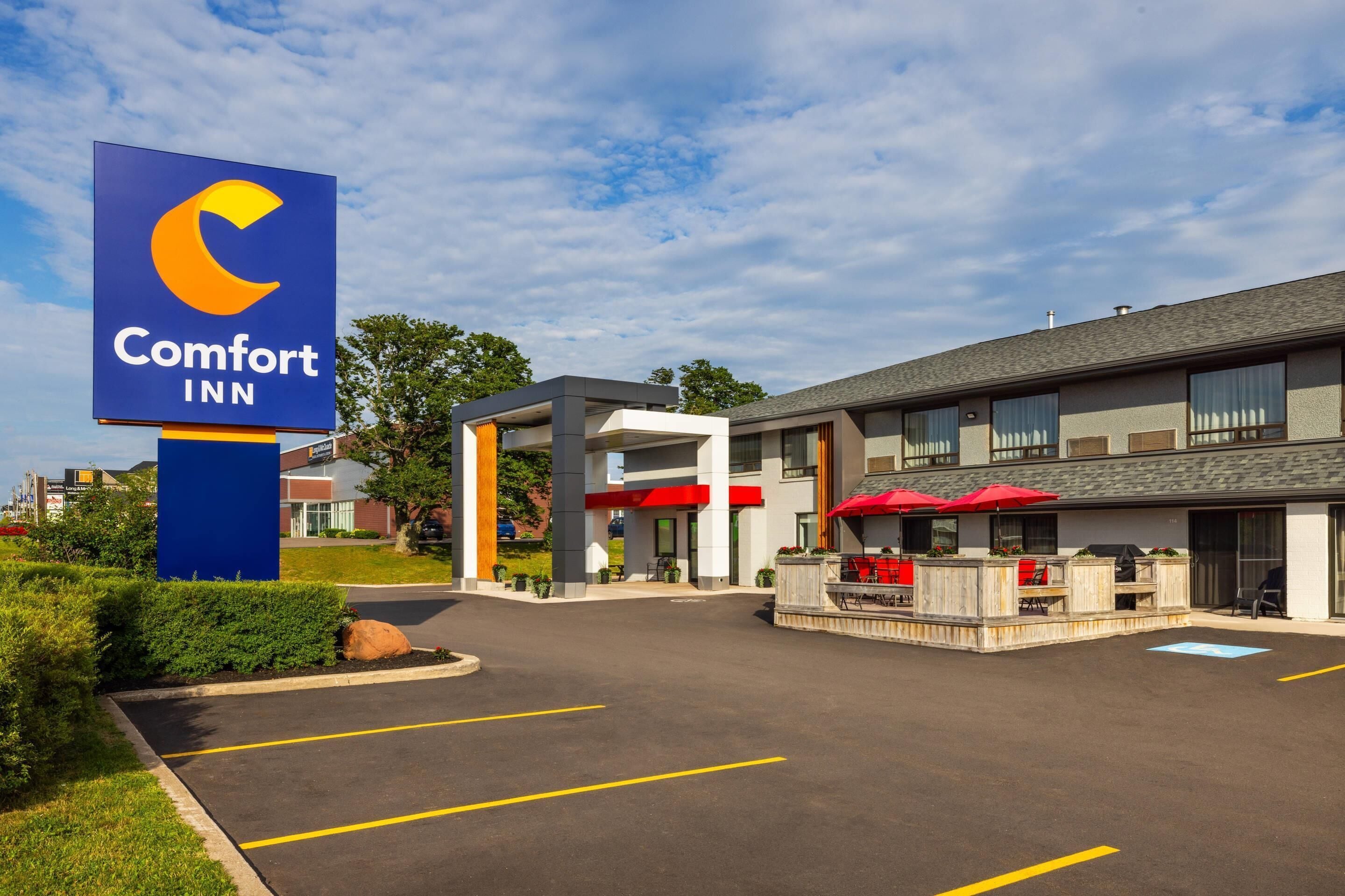 Un hotel Comfort Inn con un letrero grande, zona de estar al aire libre y aparcamiento.