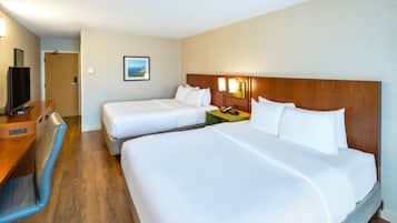 A hotel room with two beds, a desk, a chair, and a television.